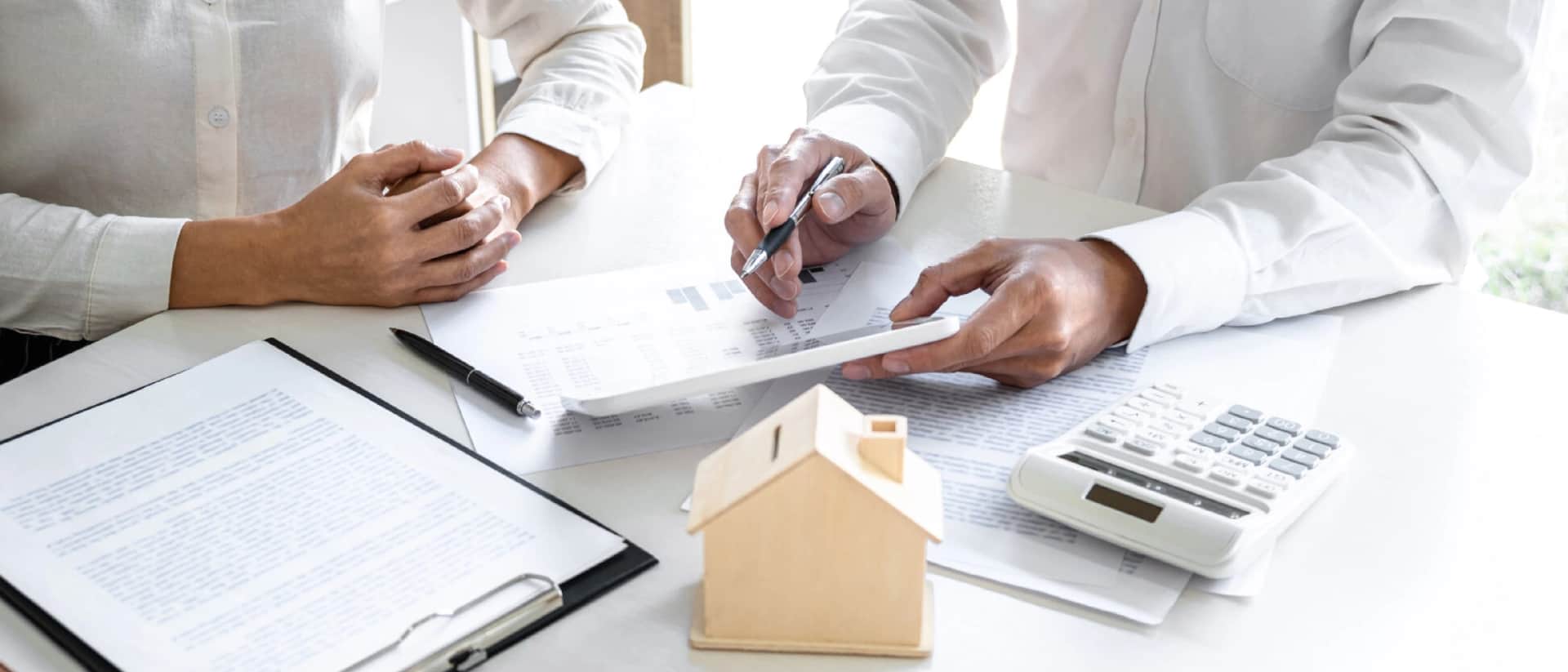 Two people at table with model house, documents