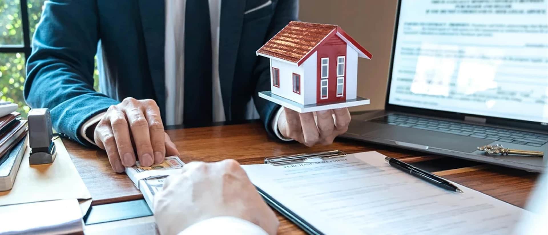 A man in a suit hands money for a small house