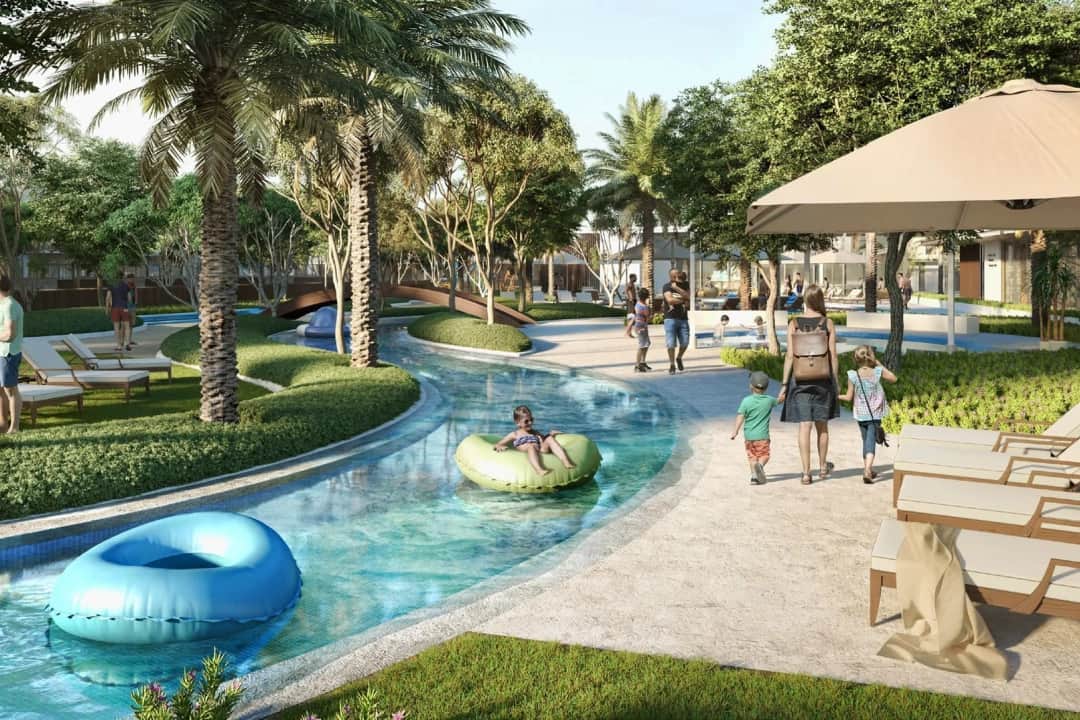 Family walking along a lazy river with palm trees, tubes
