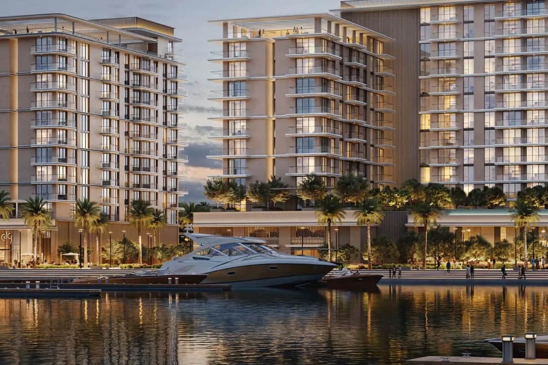أبراج سكنية مع مرسى وممشى تصطف على جانبيه أشجار النخيل عند الغسق