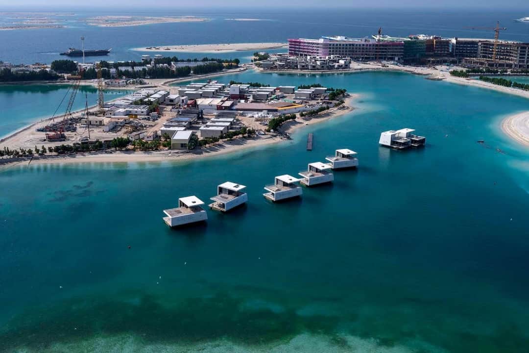 Aerial view of floating villas and a construction site by the sea