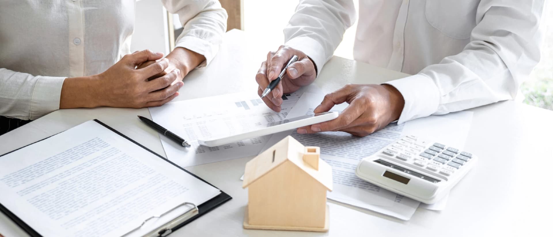 Two people at table with model house, documents