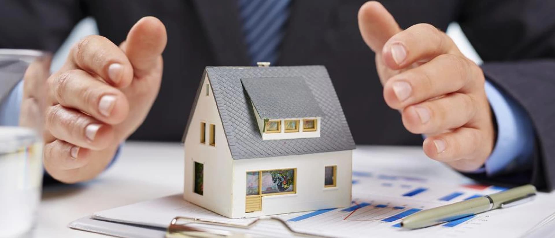 Hands protect model house on table