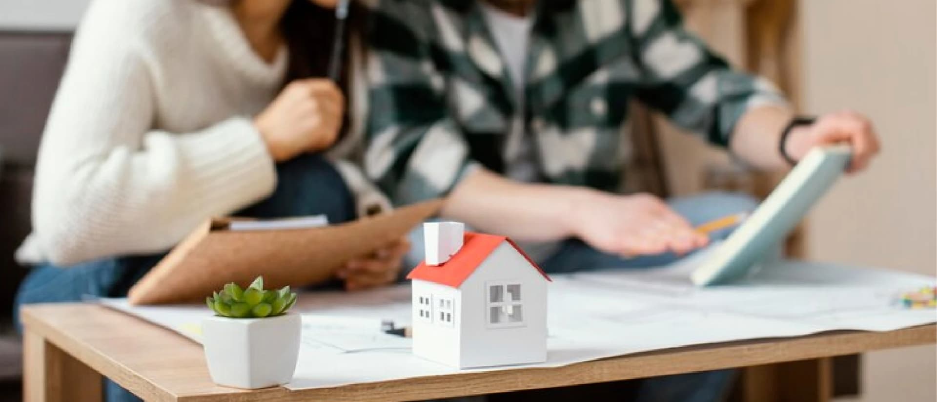 A couple reviews blueprints with a house model