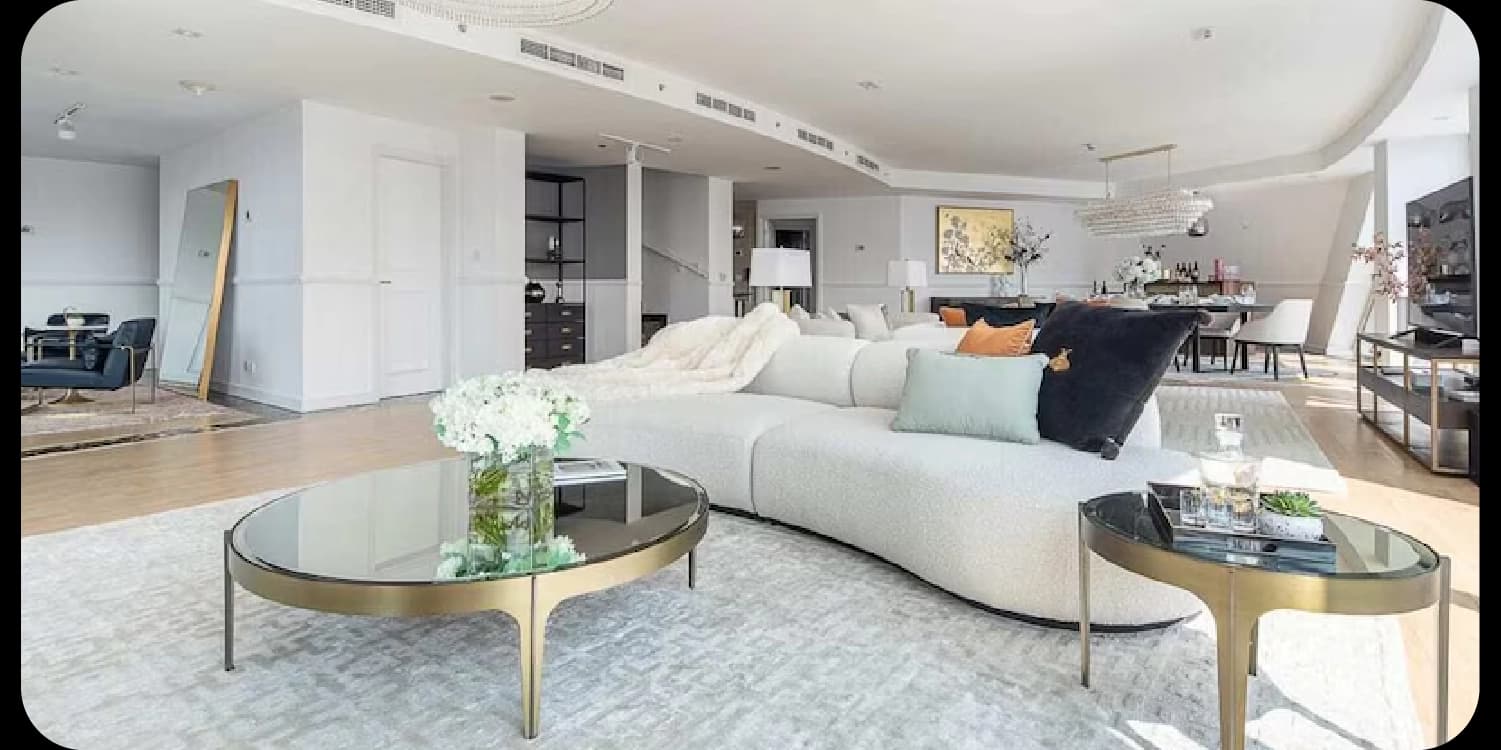 Spacious, modern living room with curved sofa and glass tables