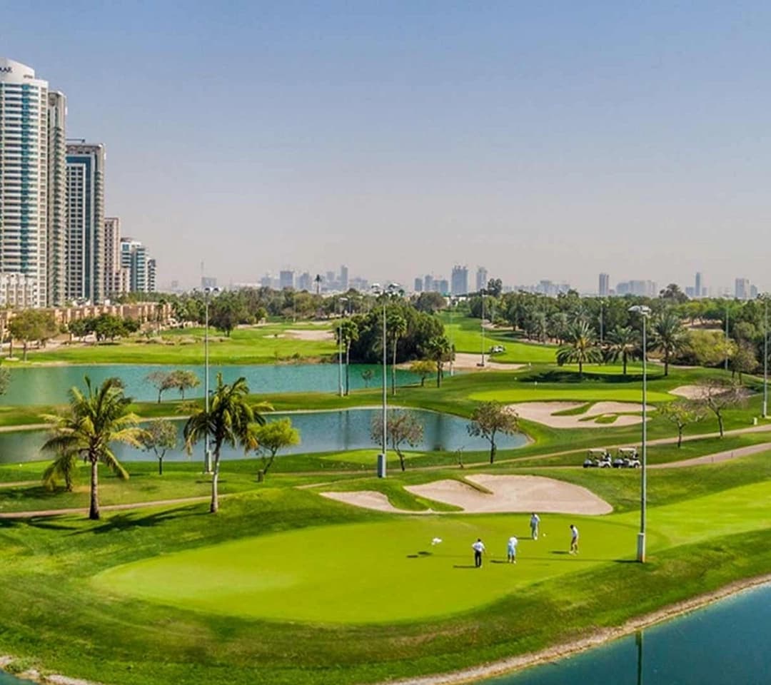 Aerial view of green golf course, palm trees, buildings
