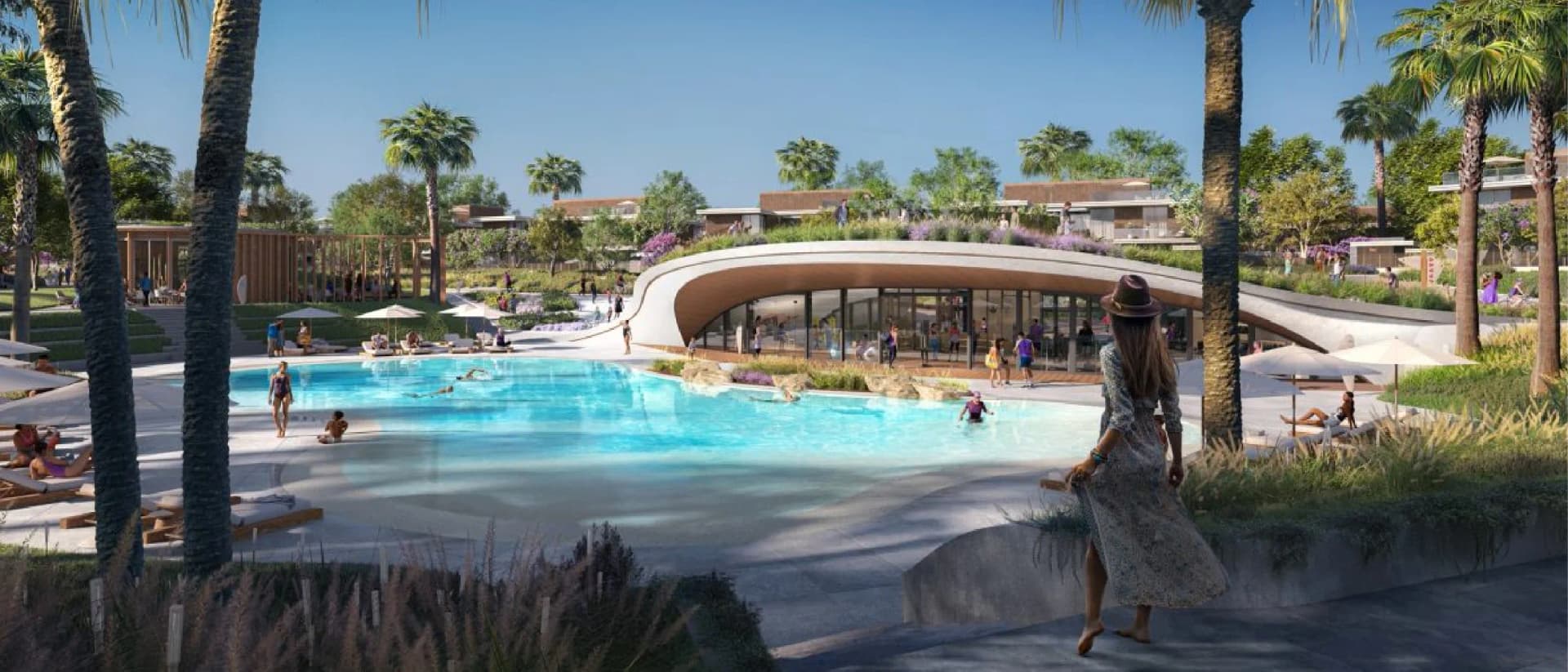 Person overlooks pool, palm trees, and buildings