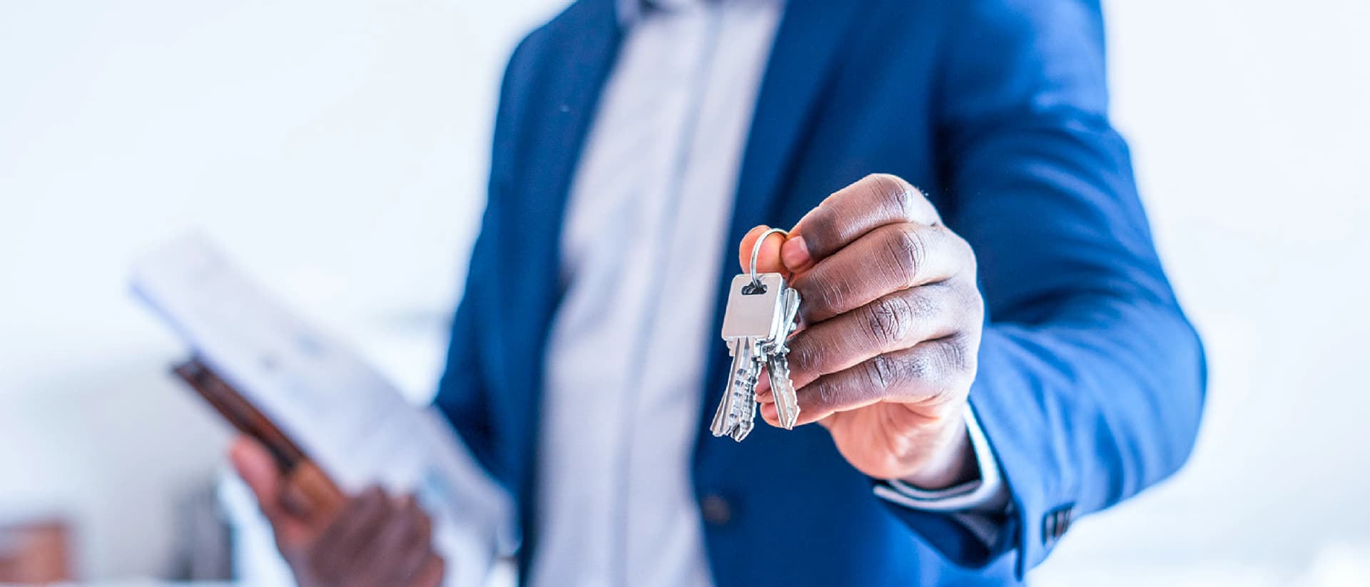 Person in blue suit holding out keys