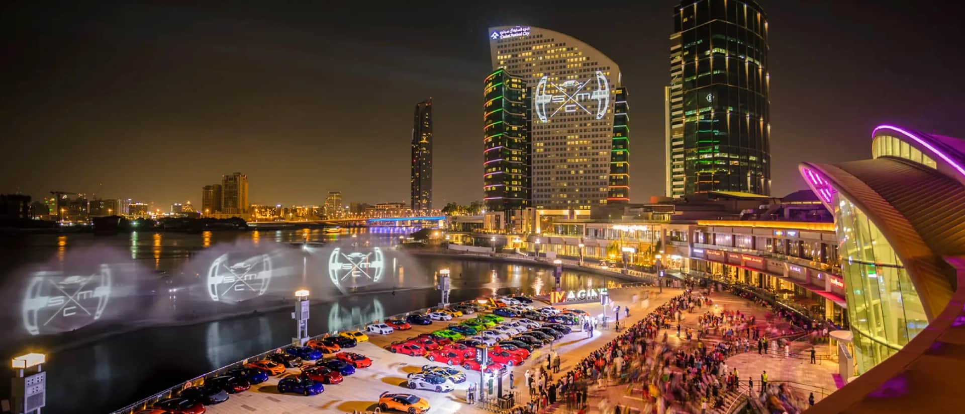 منظر ليلي لمول جراند عجمان مع سيارات فاخرة وحشد من الناس