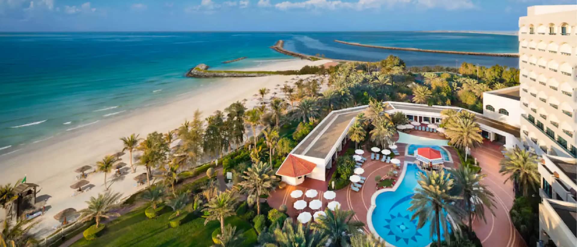 Resort with beachfront, pool, and lush palm trees by the sea
