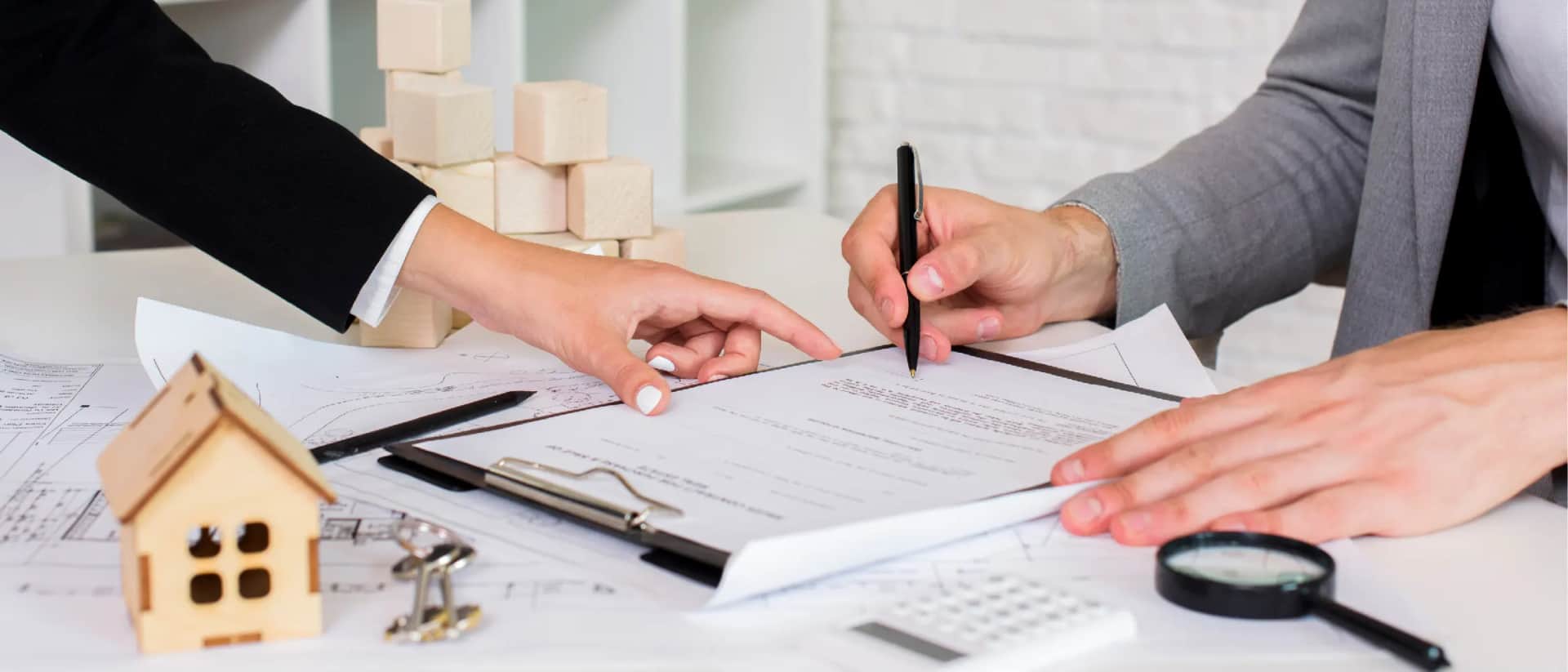 Business professionals signing contracts with architectural plans