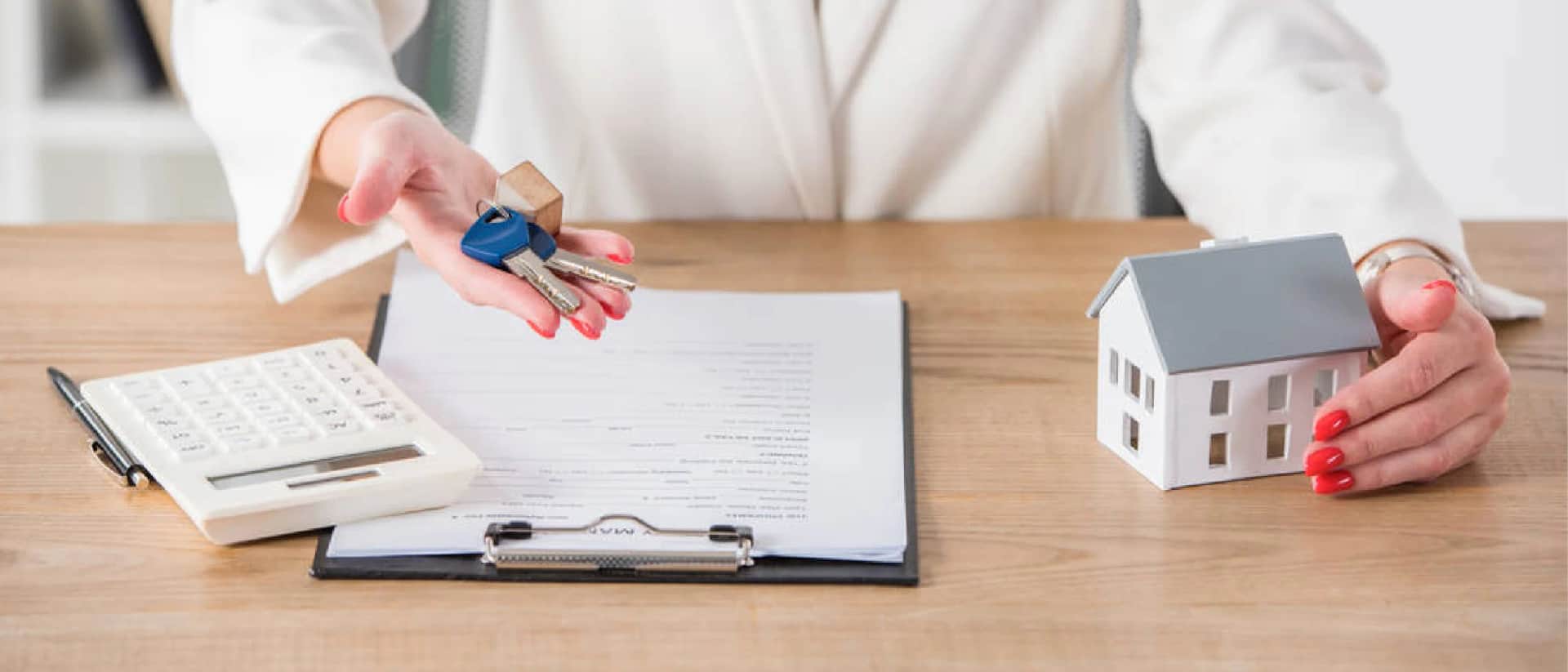 Person holding keys and house model with documents
