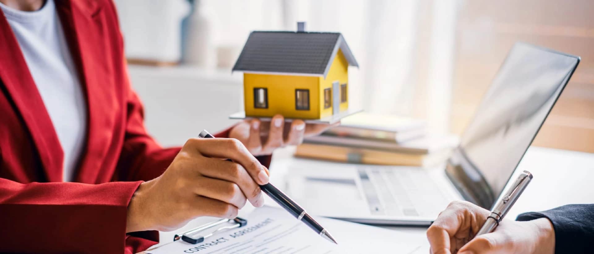 Person holds model house; other signs contract