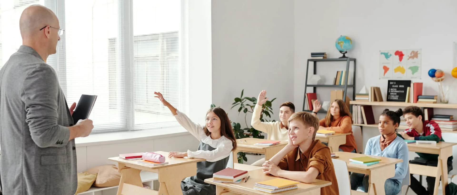 Classroom teacher with students raising hands to answer