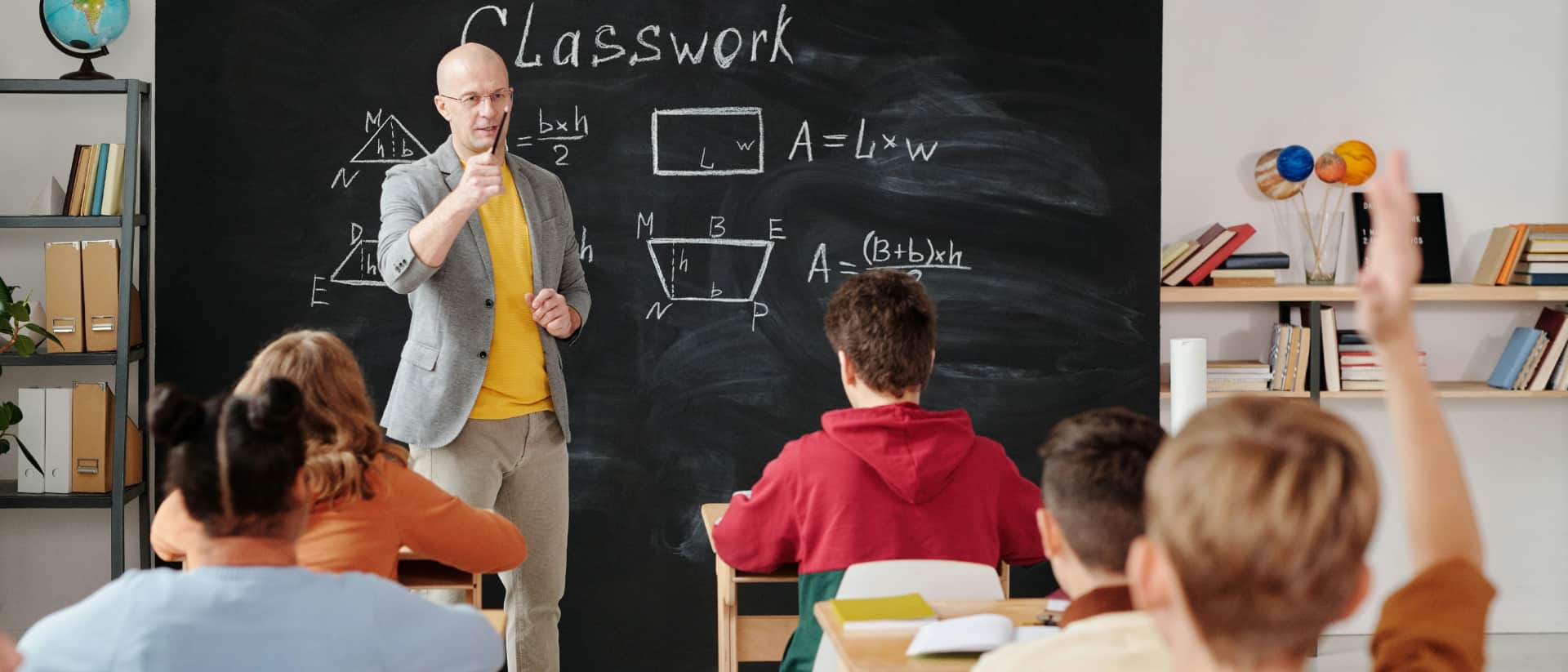 A teacher explains geometry to students in a classroom